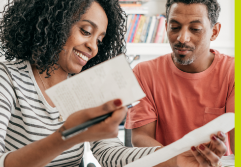 photo of a Black couple looking at financial records and smiling