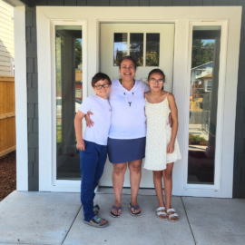 LaVena posting at the front door of her Habitat home, with her son to her right and her daughter to her left